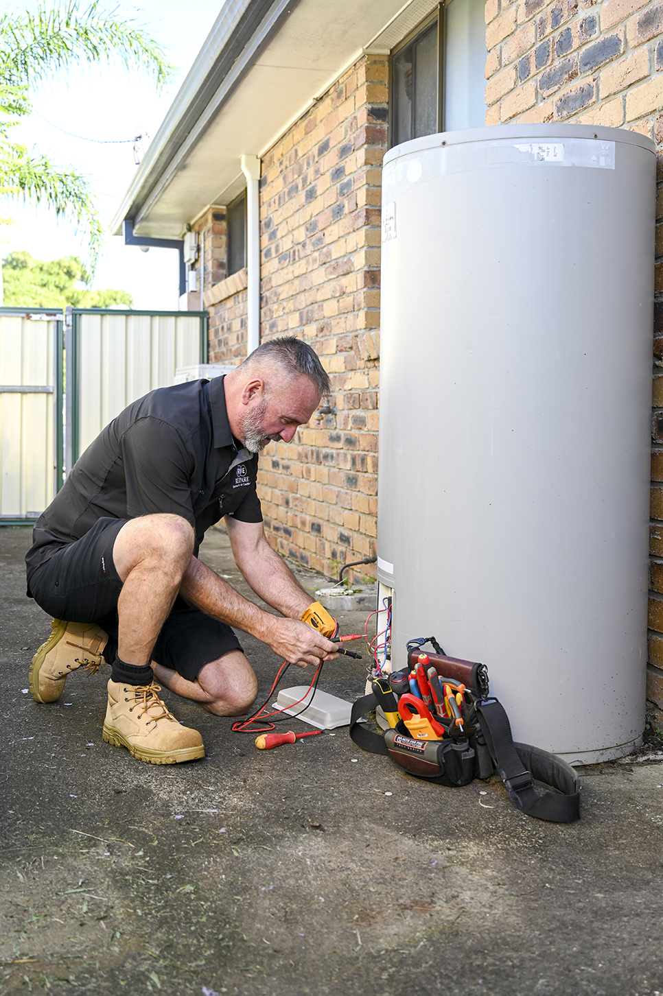 Ducted air conditioning electrician Loganholme, technician balancing airflow at ceiling vents and checking return air grille performance.