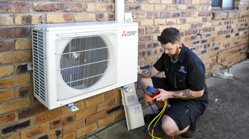 Electrician Loganholme technician testing safety switches and checking circuit labels inside a modern switchboard.