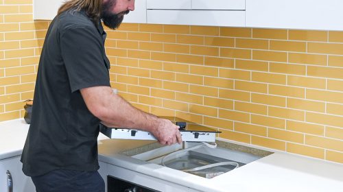 Home electrical fault finding Loganholme, electrician testing a tripping circuit at the switchboard and inspecting an outdoor power point for moisture ingress.