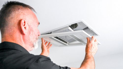 Air conditioning electrician Loganholme inspecting a split system indoor unit, checking airflow and clearing a blocked condensate drain.