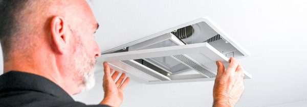 Emergency electrician Loganholme technician inspecting a residential switchboard at night with a torch and test meter.