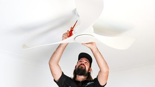 Licensed electrician testing a modern switchboard while carrying out electrician Loganholme safety checks in a family home.