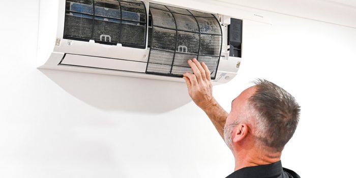 Electrician completing ceiling fan installation Loganholme, adjusting a modern white fan in a family living room.